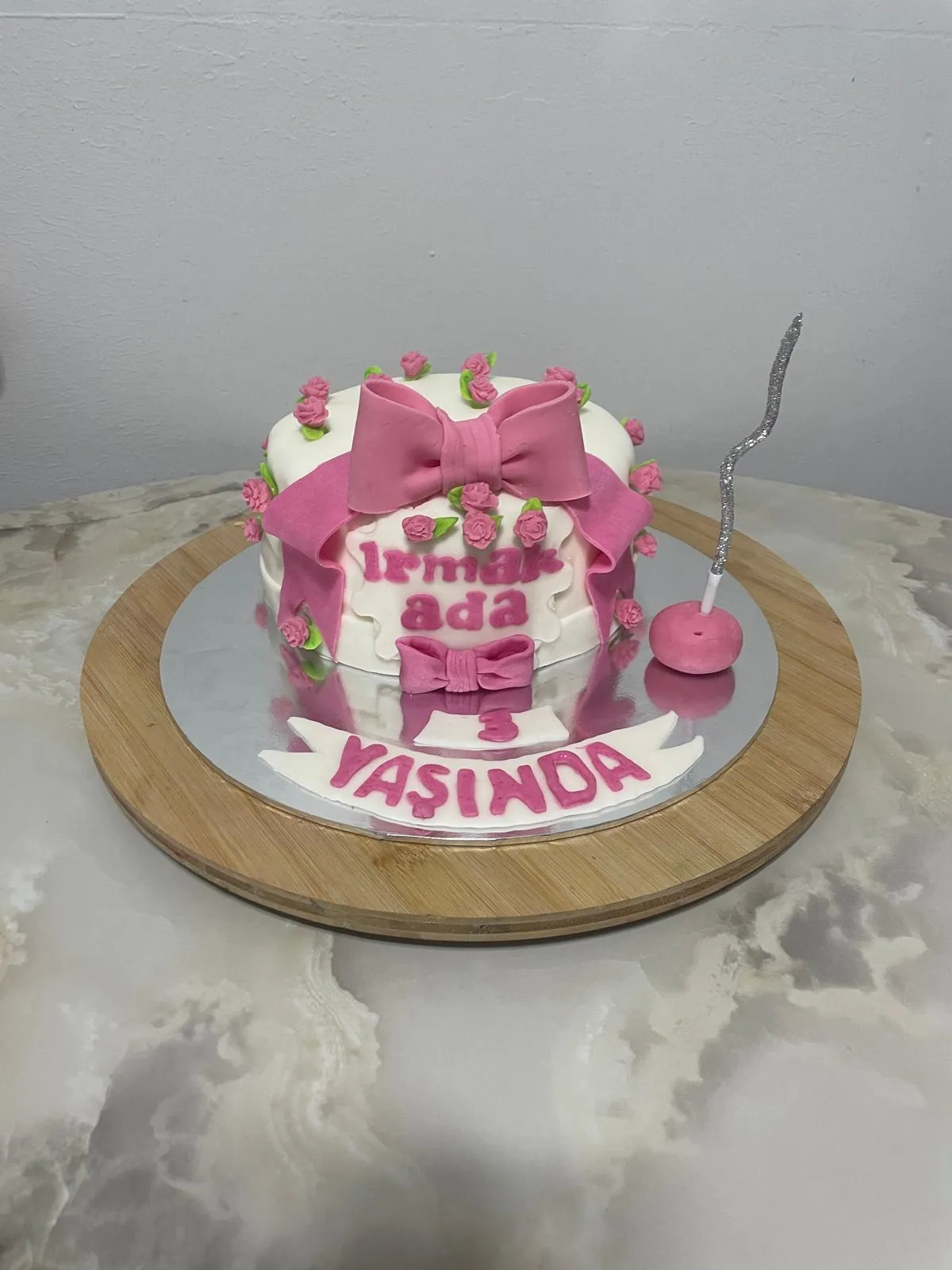 Pembe ve beyaz fondanlı, kurdele detaylı doğum günü pastası